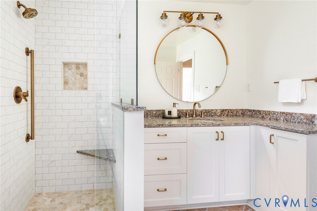 Beautifully updated hall bathroom servicing two nearby bedrooms with custom vanity, stone counters and seamless glass shower.
