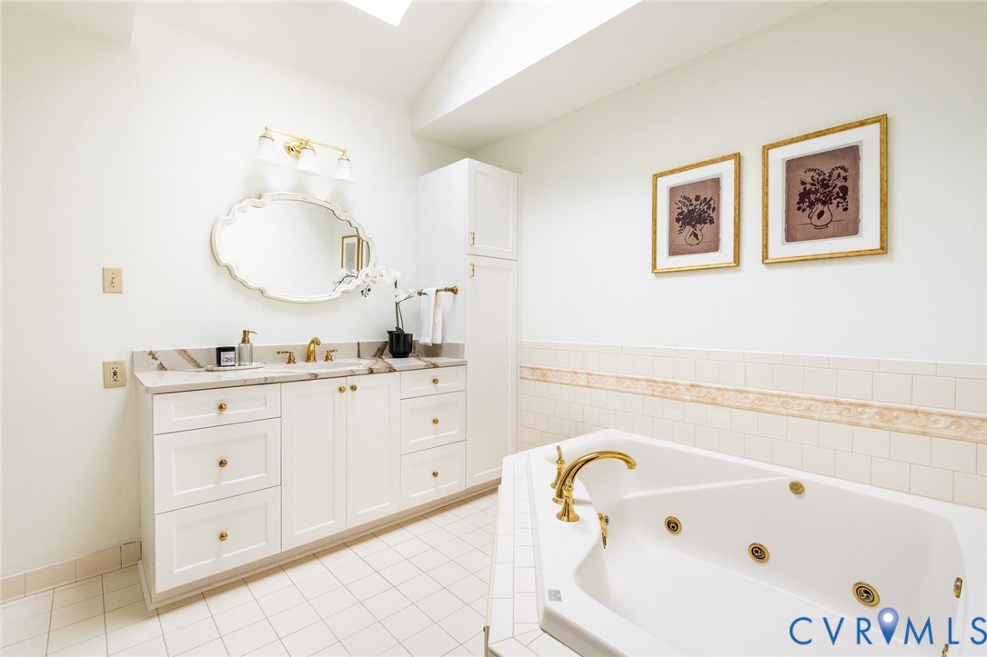 Primary ensuite bathroom with garden jacuzzi bath tub, glass shower, skylight and custom vanity.