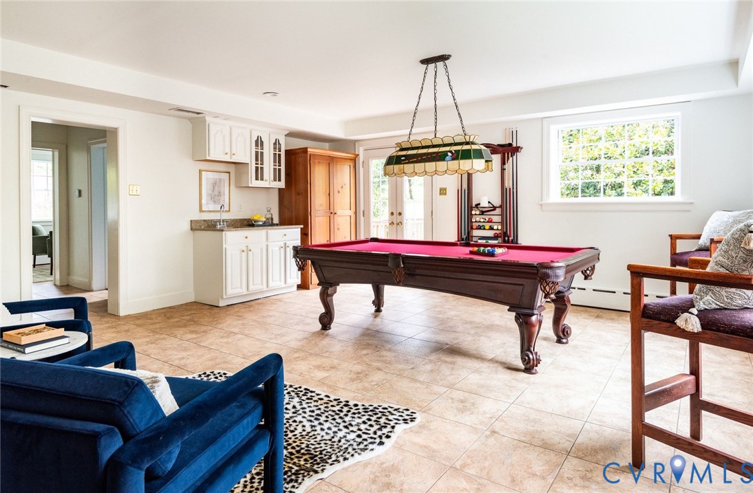 An entertainer's paradise rec room with wet bar, custom built-ins, access to private deck overlooking substantial sweeping yard, nearby full bathroom and access to the garage/workshop.
