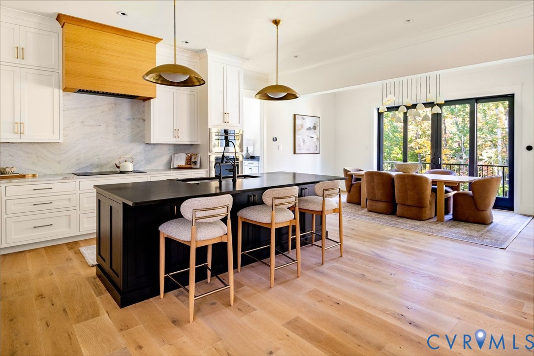 Chefs kitchen with premium appliances, Wolf induction cooktop, hidden pantry, quartzite island, leathered marble counters, access to multifunctional mudroom, open to dining and living areas.