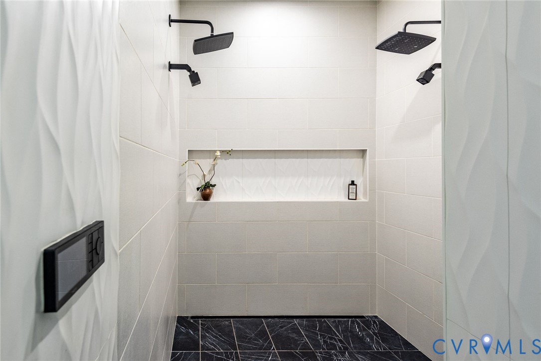 Spa-inspired primary ensuite with seamless shower featuring dual shower heads and custom niche with designer tile.