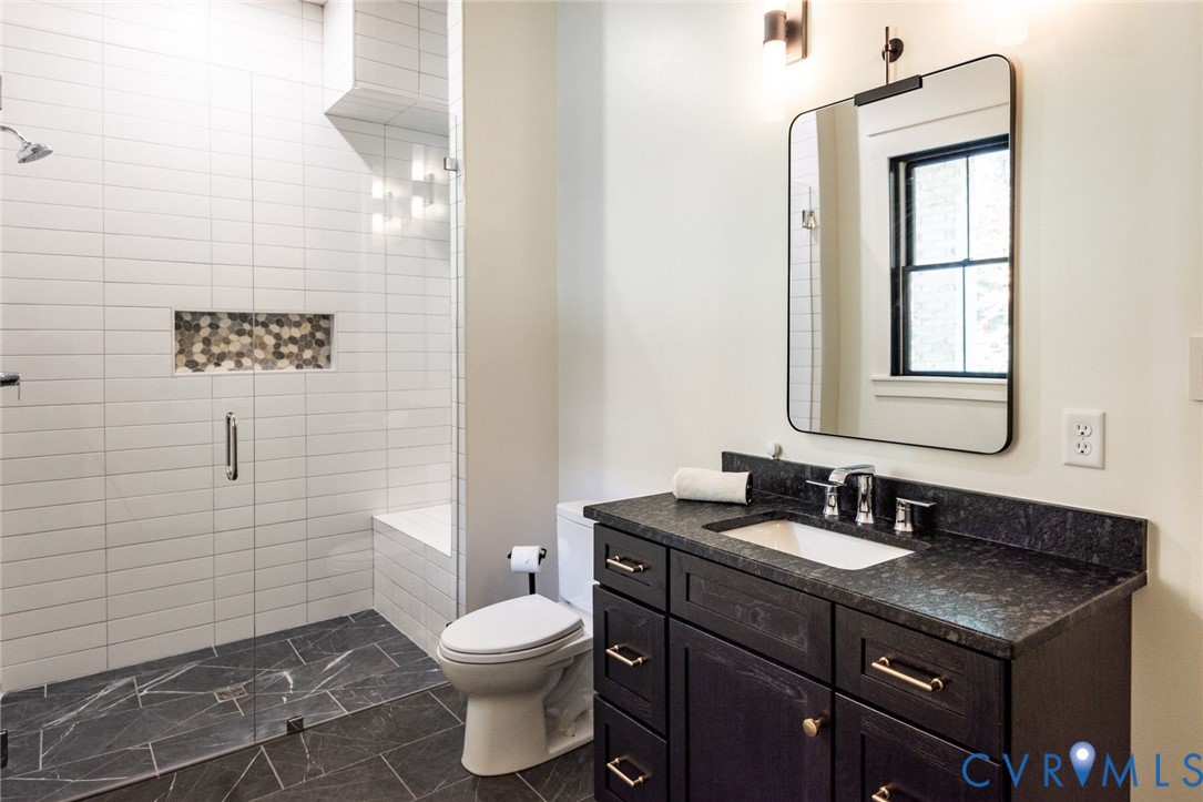 Lower level full bathroom with seamless entry glass shower, custom vanity and exterior door access- perfect for future pool plans!