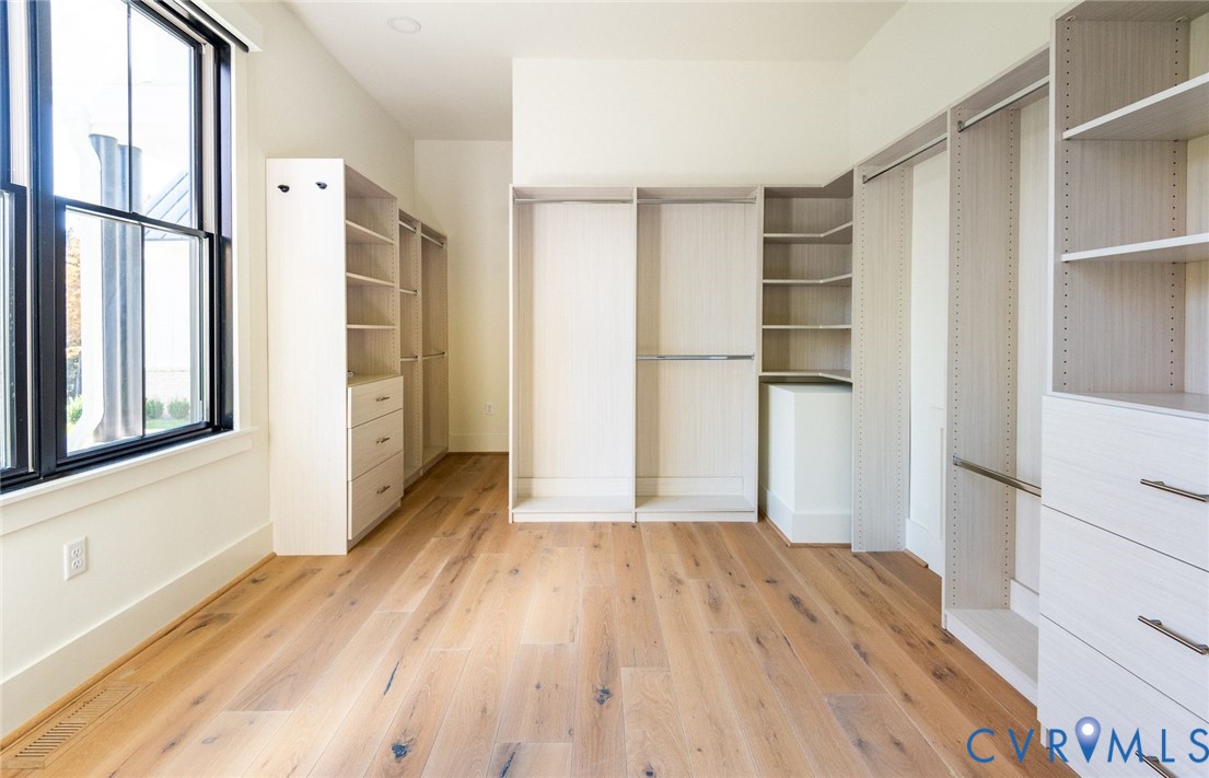 Custom primary walk-in closet with hardwoods and great natural light.