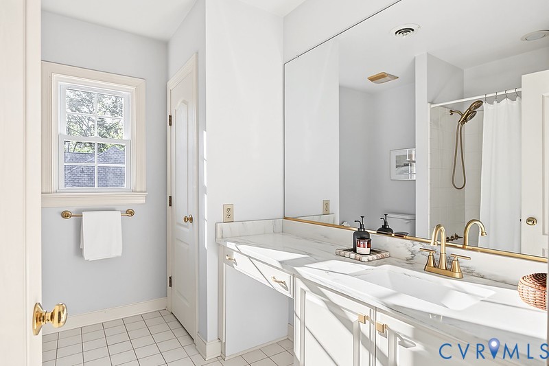 Bedroom 4's full bathroom with new quartz counters, new brass fixtures, linen closet and timeless tile flooring.