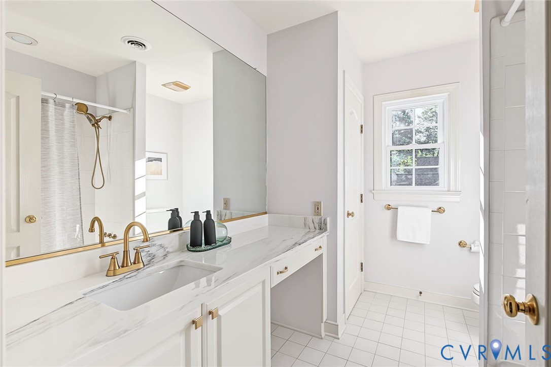 Bedroom 3's full bathroom with new quartz counters, updated brass fixtures and timeless tile flooring.