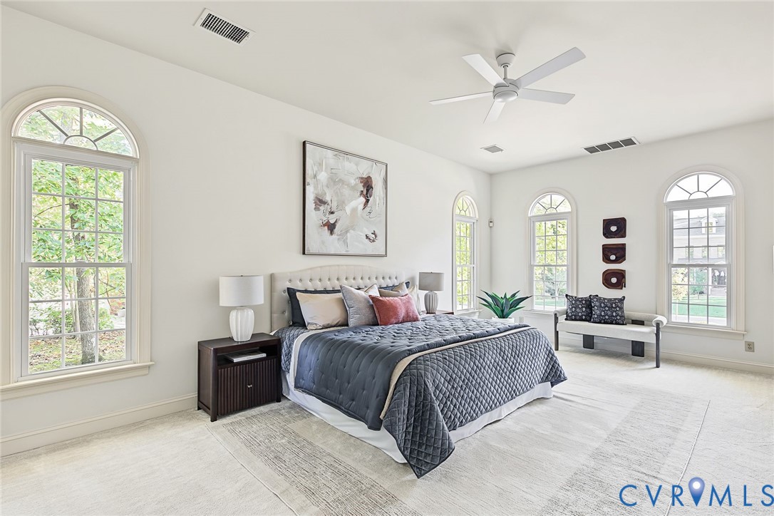 Luxurious first floor primary with serene palette, two walk in closets and new ceiling fan.