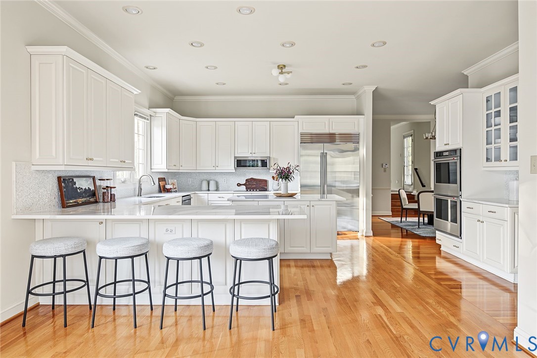 Extensive quartz counters, crisp white cabinetry, tiled backsplash in this showstopping kitchen.