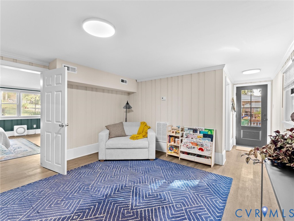 Neutral wall paneling, wood-finish flooring, and exterior door with glass insert