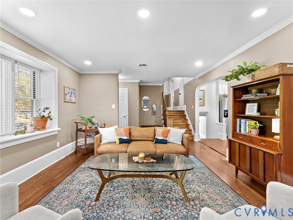 Living area featuring recessed lighting, crown molding, wood-finish flooring, a deep-sill window, and a wood staircase