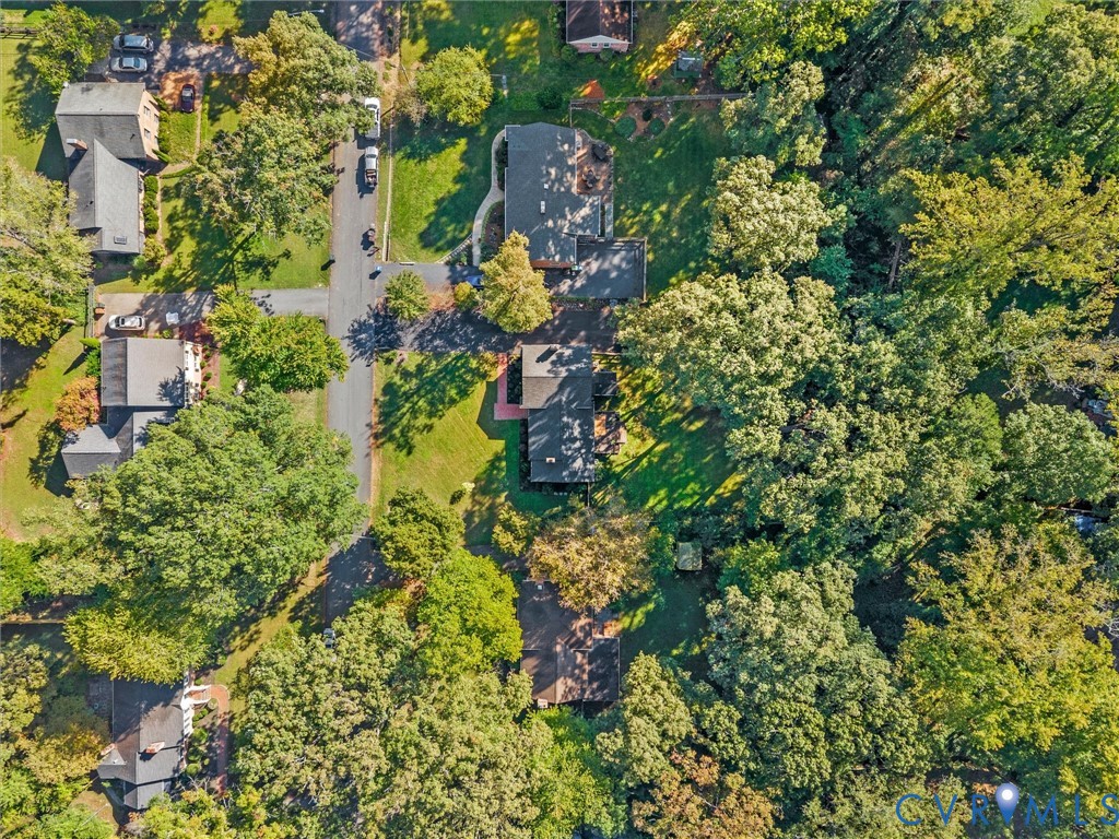 Aerial perspective of the lot featuring extensive mature tree coverage, an asphalt driveway, and a large grass lawn Aerial perspective of the lot featuring extensive mature tree coverage, an asphalt driveway, and a large grass lawn