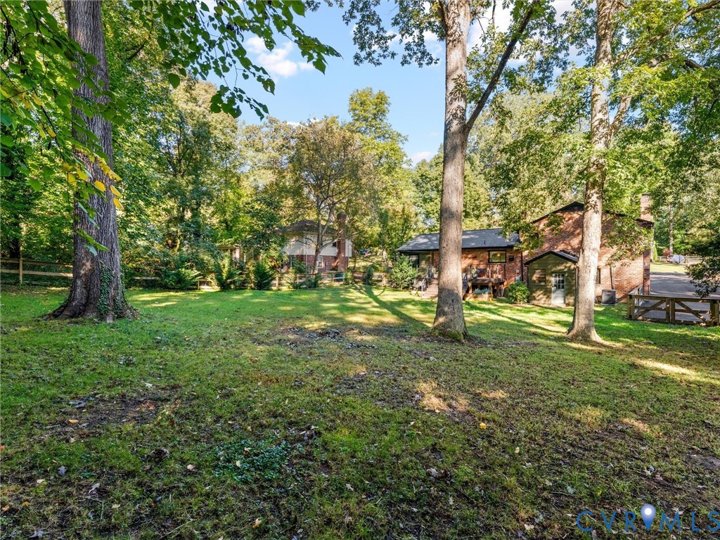 Expansive backyard featuring mature trees, a manicured lawn, and wood-style fencing