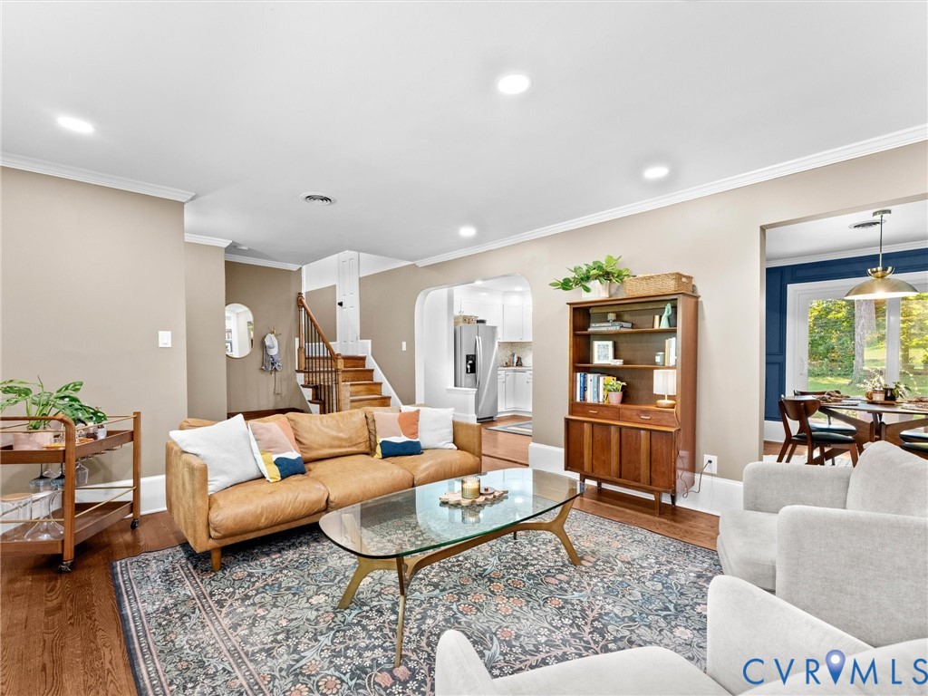 Living area featuring hardwood flooring, recessed lighting, crown molding, and an arched entryway