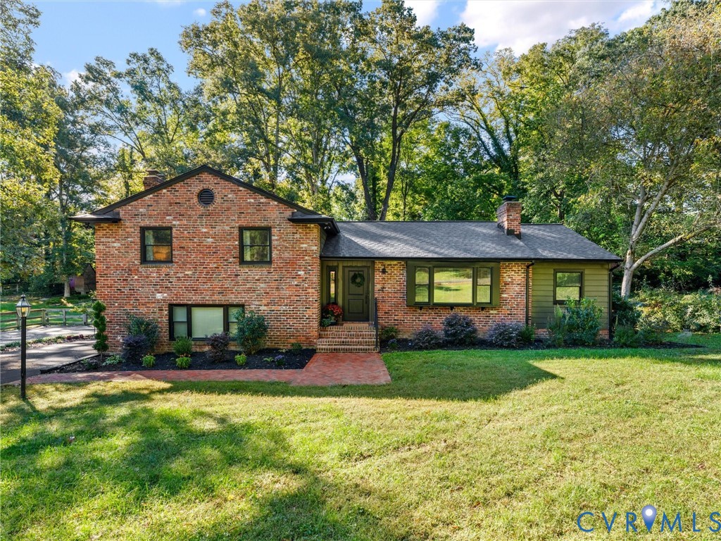 Multi-level brick exterior featuring a shingled roof, horizontal siding accents, an integrated chimney, and a brick walkway