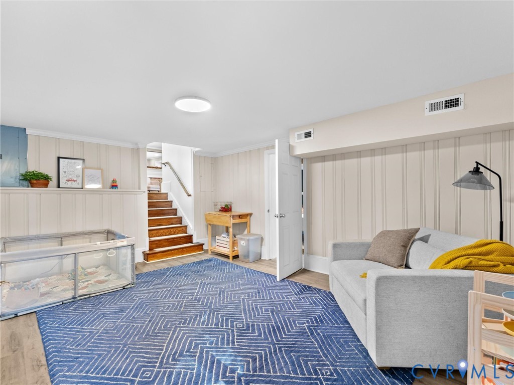 Finished interior space featuring vertical wall paneling, wood-finish flooring, and a staircase with stained wood treads