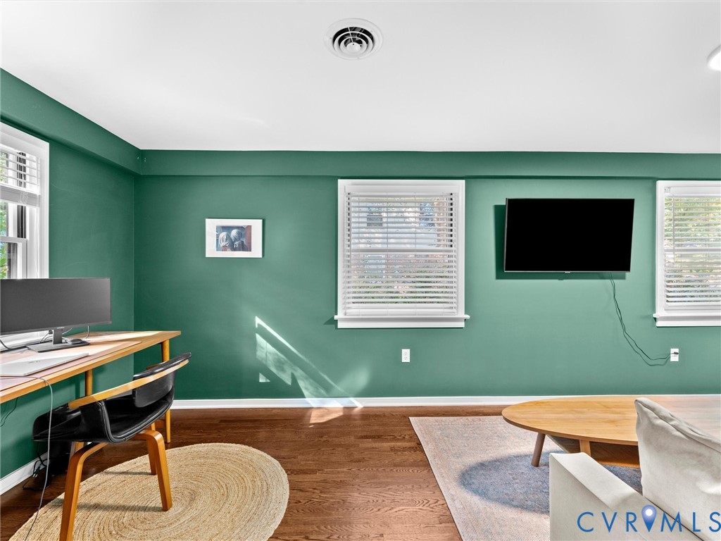 Wood-finish flooring and multiple windows with installed horizontal blinds