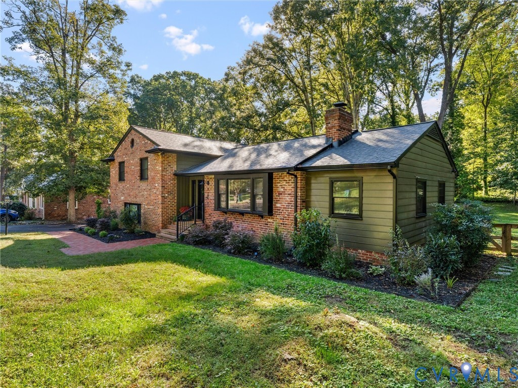 Exterior featuring a combination of brick and horizontal siding, a prominent brick chimney, a bay window, and a red brick walkway