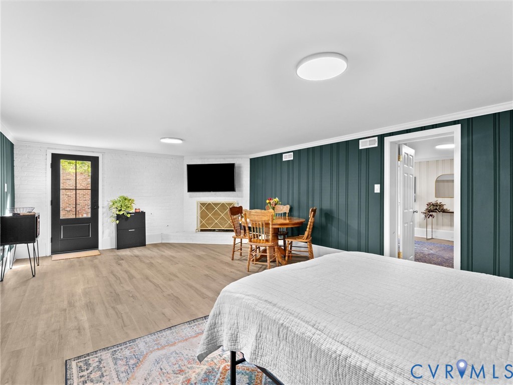 Wood-finish flooring, dark-toned vertical paneled wall, white painted brick, and exterior access door with glass pane