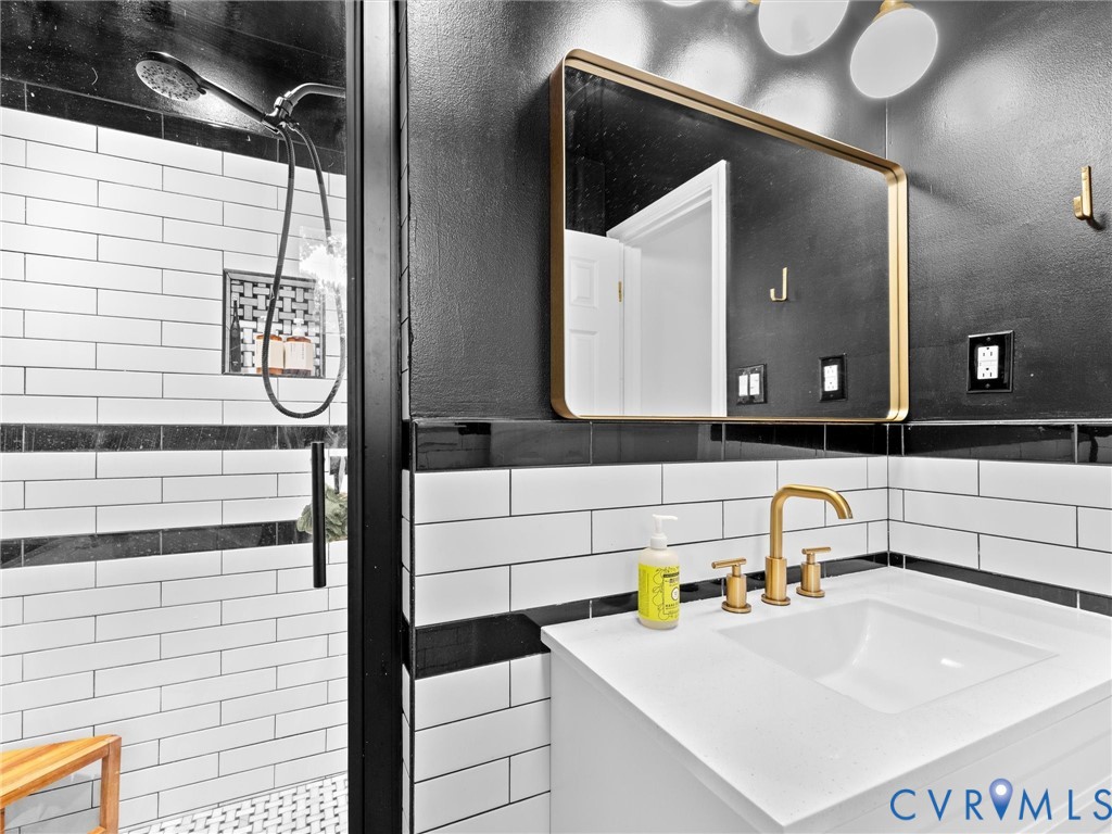 Modern vanity featuring a white countertop with an integrated basin, gold-finish widespread faucet, and brass-framed rectangular mirror