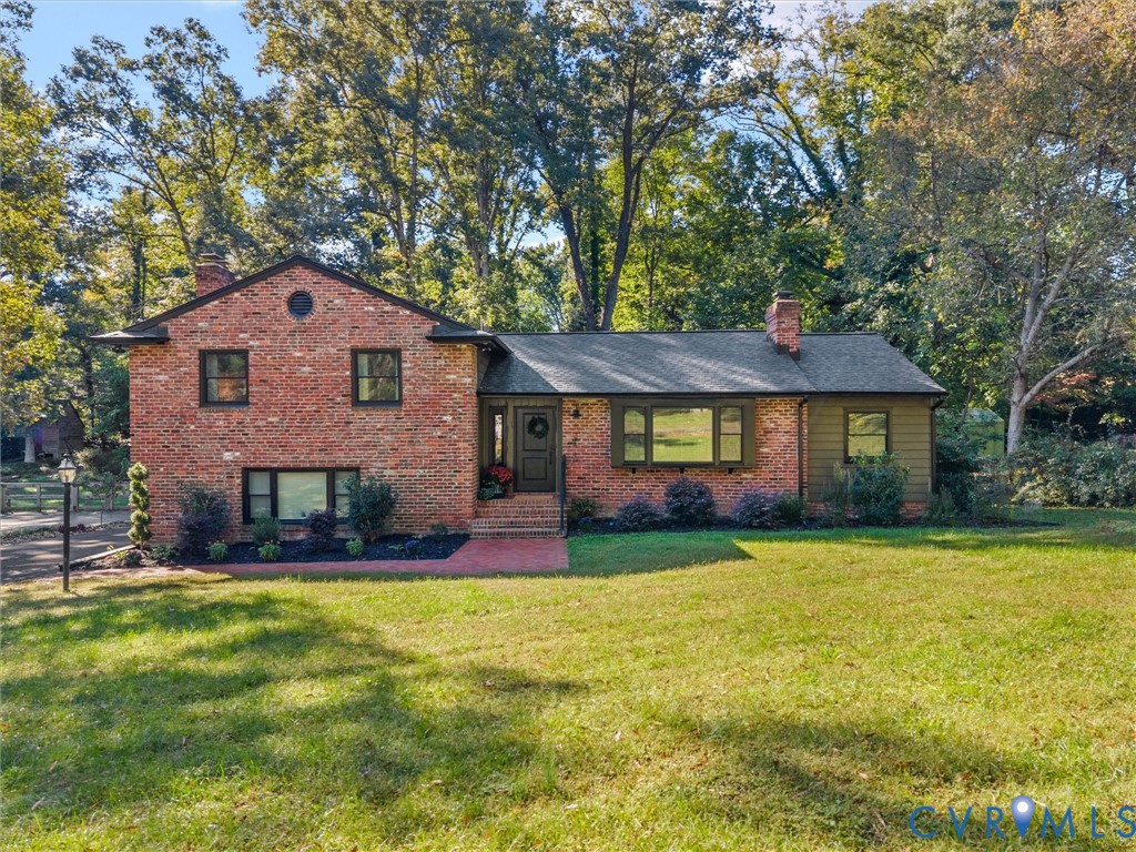 Multi-level brick exterior featuring a shingled roof, horizontal siding accents, an expansive front lawn, and mature trees Multi-level brick exterior featuring a shingled roof, horizontal siding accents, an expansive front lawn, and mature trees