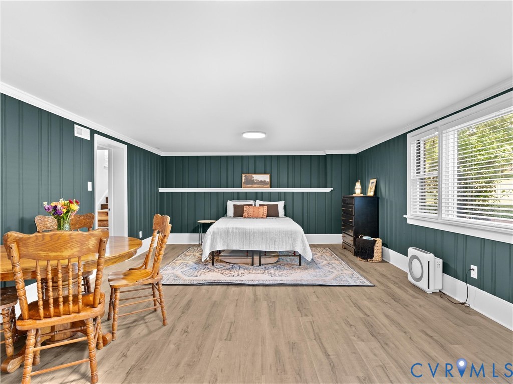 Deep teal vertical board-and-batten wall paneling featuring a horizontal chair rail shelf, wood-finish flooring, and large multi-pane windows with horizontal blinds
