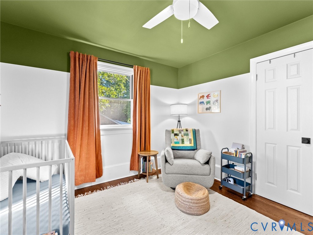 Hardwood flooring, two-toned wall paint, white six-panel interior door, and a white ceiling fan with integrated lighting