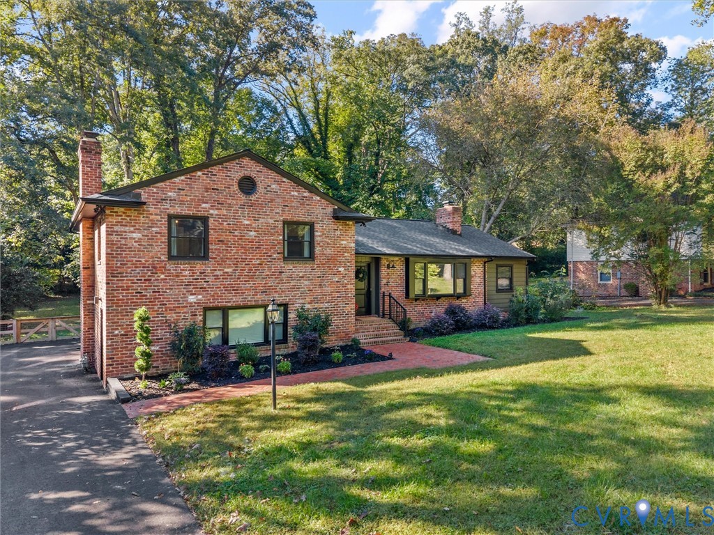 Classic brick exterior featuring a multi-level roofline, a bay window, a paved walkway, and mature landscaping Classic brick exterior featuring a multi-level roofline, a bay window, a paved walkway, and mature landscaping