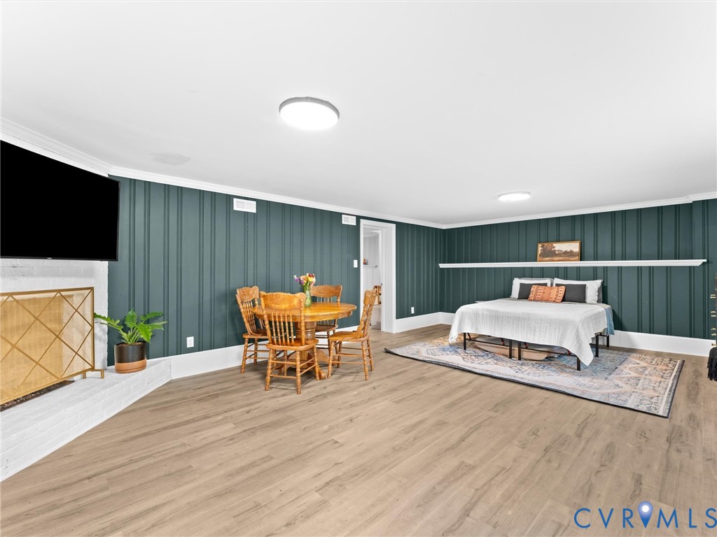 Vertical plank wall paneling, wood-finish flooring, white brick fireplace surround, and built-in mantle ledge
