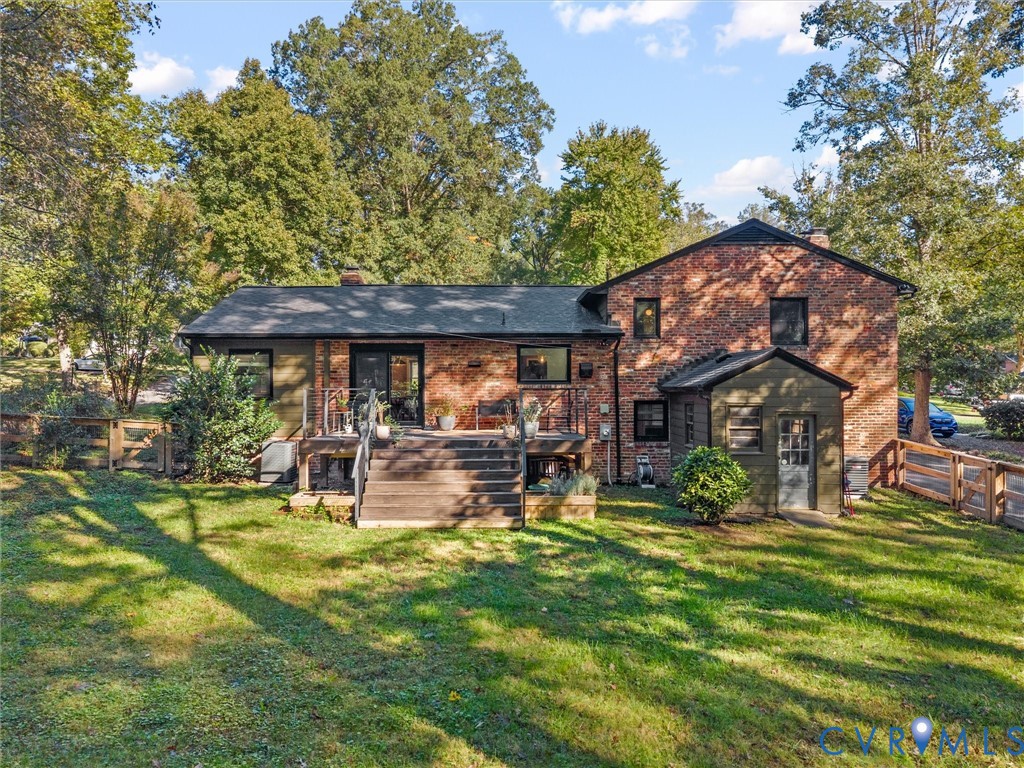 Brick exterior featuring a rear wood deck, multi-level roofline, fenced perimeter, and established landscaping Brick exterior featuring a rear wood deck, multi-level roofline, fenced perimeter, and established landscaping