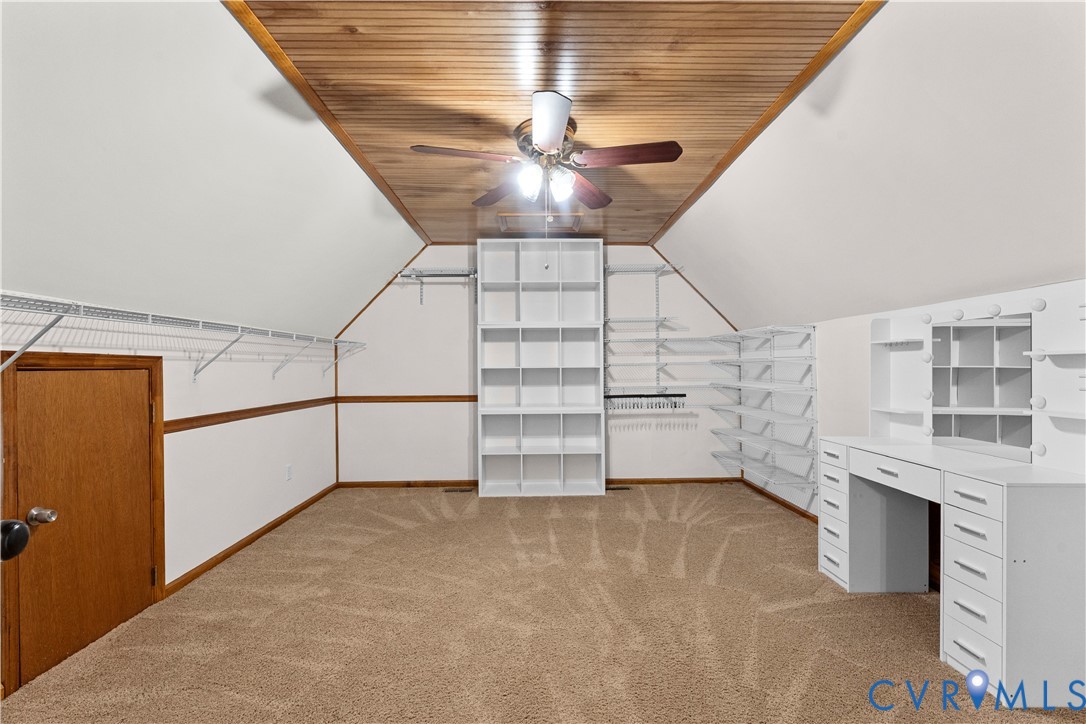 Vaulted wood-plank ceiling, wall-to-wall carpeting, integrated shelving system, built-in storage cubbies, and an attached vanity station