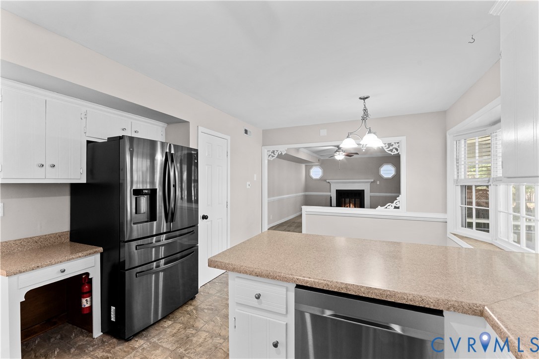 Kitchen featuring white cabinetry, solid-surface countertops, stainless steel appliances, a multi-pane bay window, and a decorative cased opening