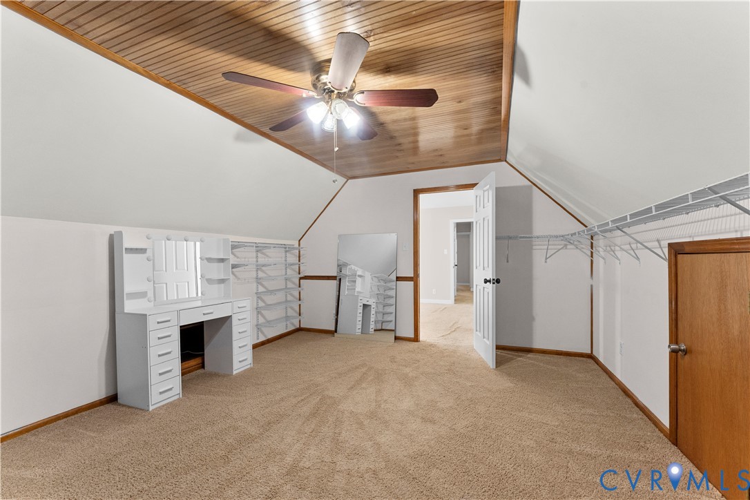 Vaulted room featuring a wood-plank ceiling, wall-to-wall carpeting, and integrated white shelving