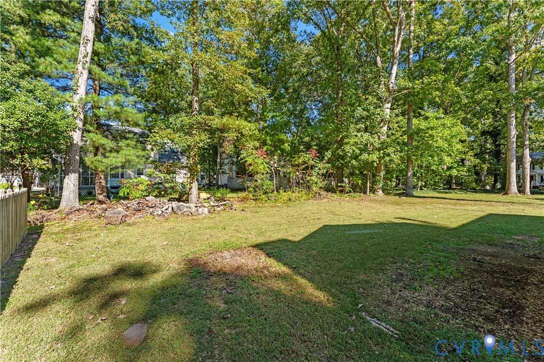 Expansive backyard featuring a lawn, mature canopy trees, and a wooden perimeter fence