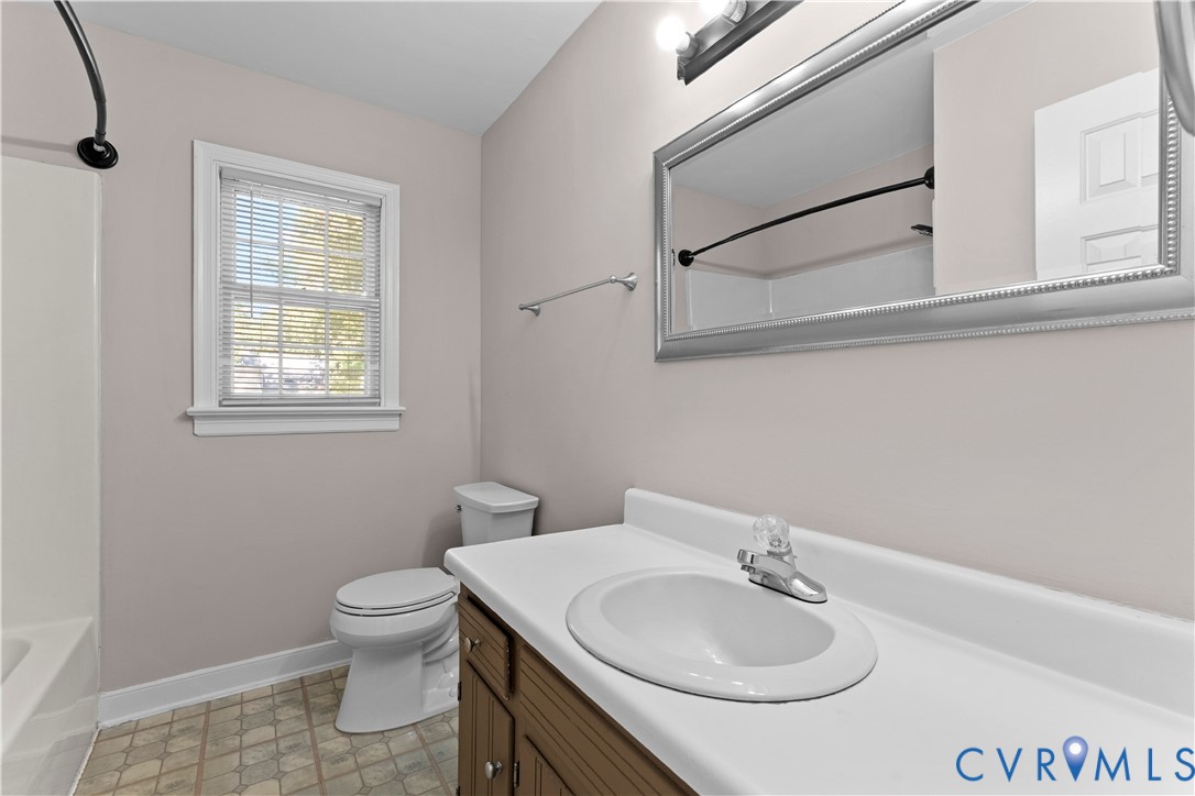 Bathroom featuring a vanity with an integrated countertop and basin, framed wall-mounted mirror, multi-light fixture, and tub-shower combination