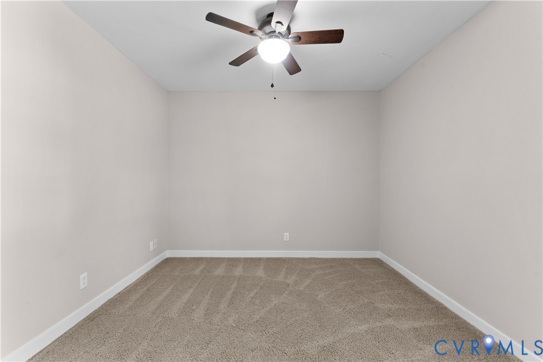 Neutral-toned interior space featuring plush carpeting and a central ceiling fan with an integrated light fixture