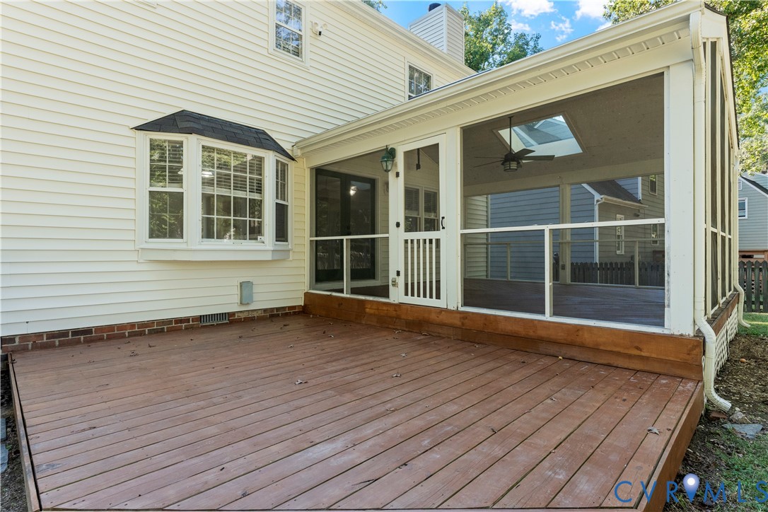 Exterior wood deck featuring a screened-in porch with a skylight, ceiling fan, and bay window