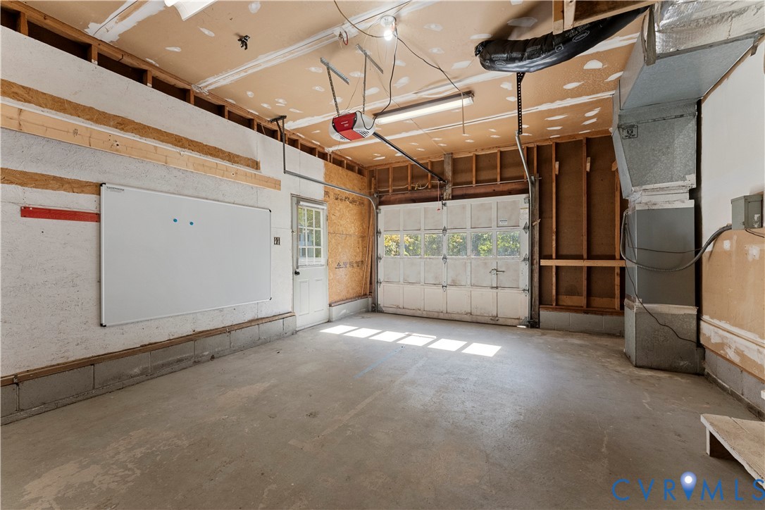 Garage space featuring a concrete floor, windowed sectional door, exterior access door, and exposed wall framing