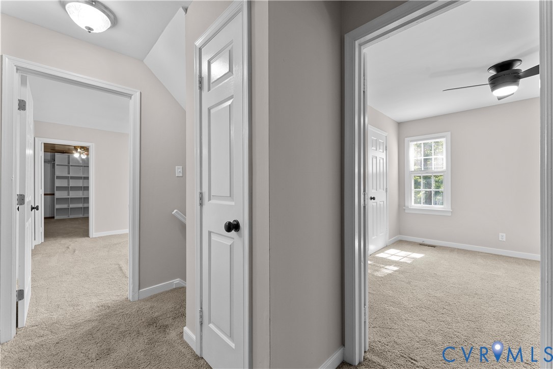 Neutral-toned interior featuring multi-panel interior doors, wall-to-wall carpeting, ceiling-mounted light fixtures, and a window with white trim