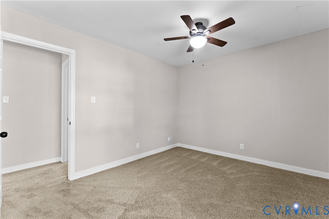 Neutral-toned interior space featuring neutral wall-to-wall carpeting and a ceiling-mounted fan with integrated light fixture
