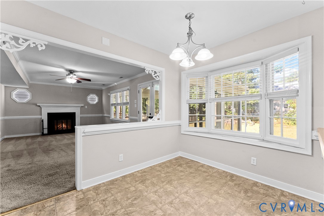 Dining area featuring a bay window, decorative crown molding trim, tile flooring, and a multi-arm chandelier