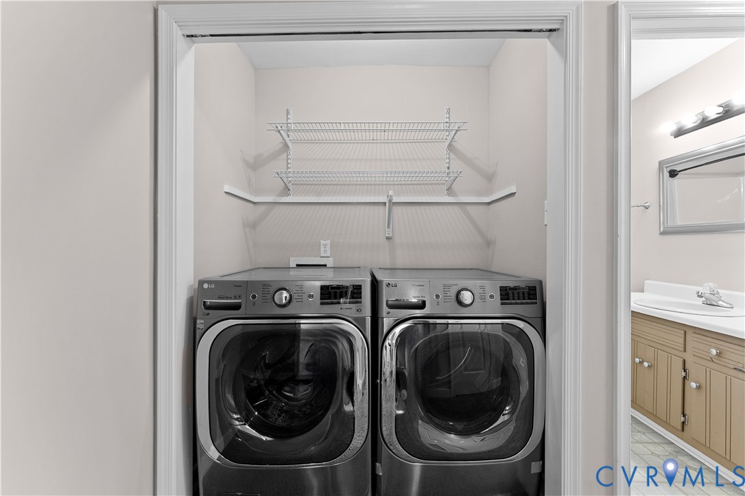 Laundry closet featuring built-in wire shelving and metallic-finish front-loading laundry appliances