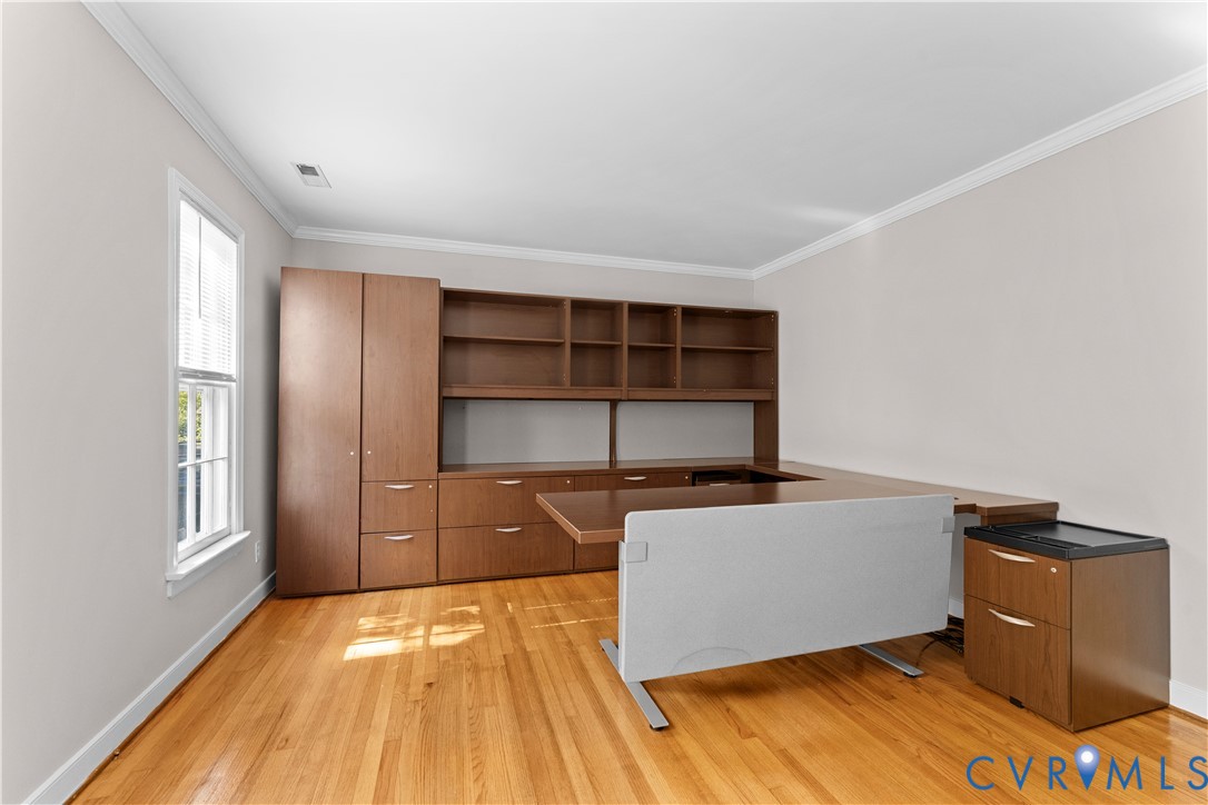 Wood-finish flooring, crown molding, and built-in floor-to-ceiling cabinetry with integrated shelving and drawers