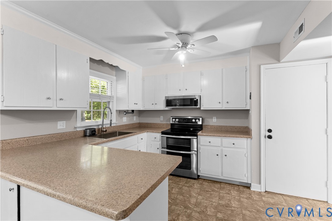 Kitchen featuring white cabinetry, solid-surface countertops, stainless steel appliances, and a ceiling-mounted light fixture