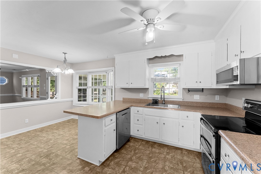 Kitchen featuring white cabinetry, solid surface countertops, stainless steel appliances, a peninsula, and a ceiling fan