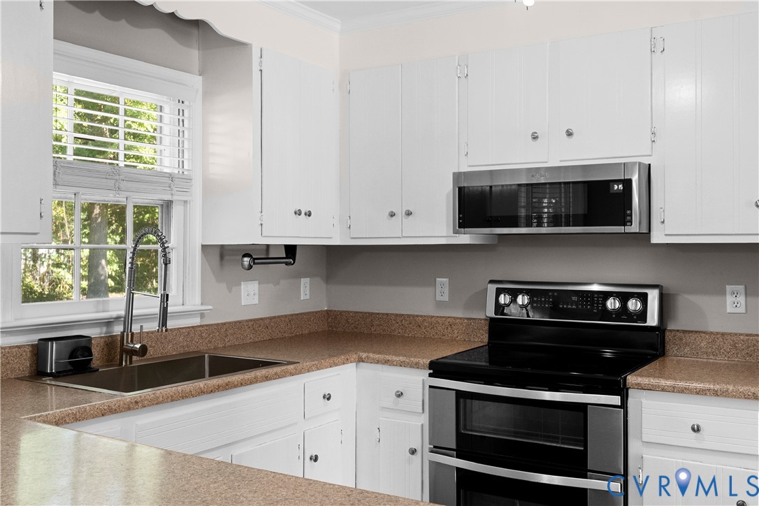 Kitchen featuring white shaker-style cabinetry, stainless steel double oven range, built-in microwave, stone-finish countertops, and an undermount sink with a gooseneck faucet
