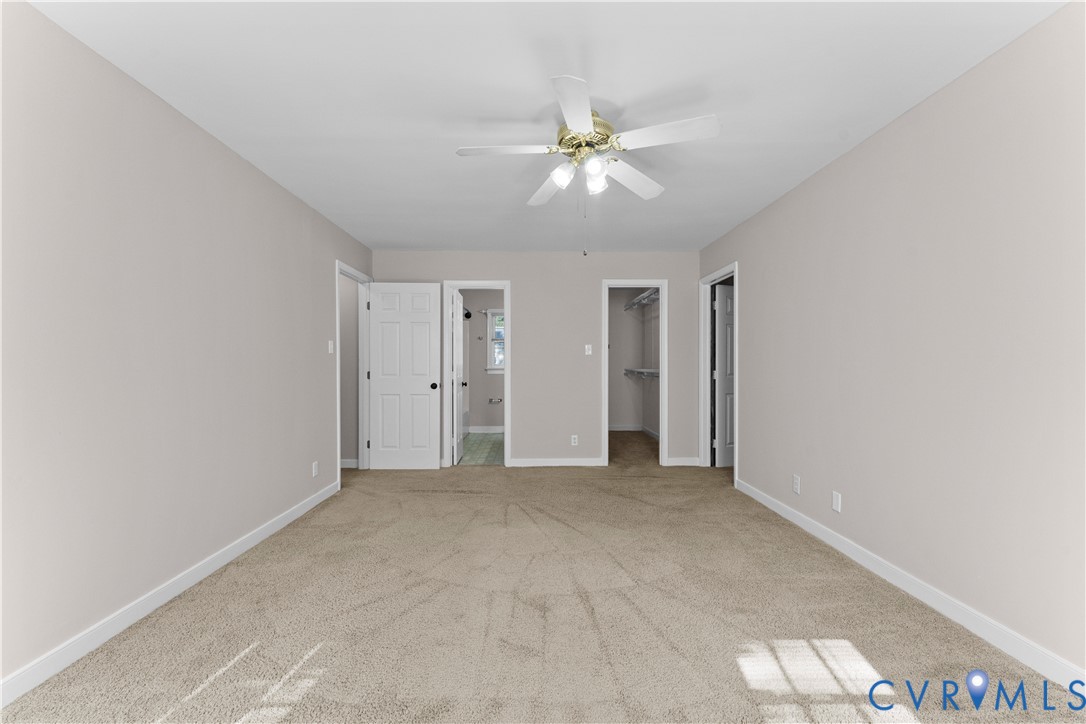Room featuring neutral-toned carpeting, white six-panel interior doors, and a ceiling-mounted light fixture with a central fan