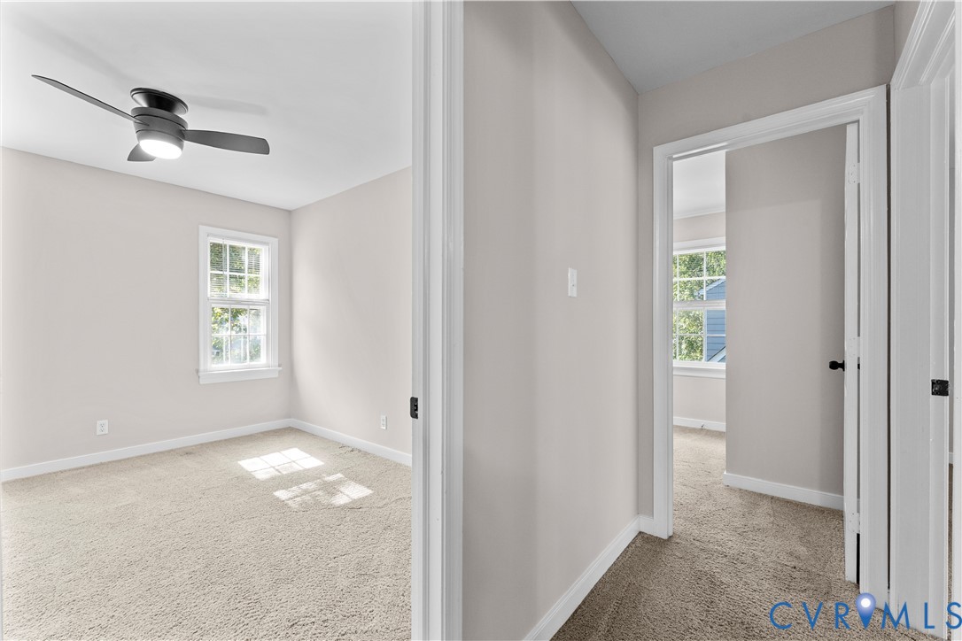 Neutral-toned interior featuring wall-to-wall carpeting, multi-pane windows, and a ceiling-mounted light fixture with a fan