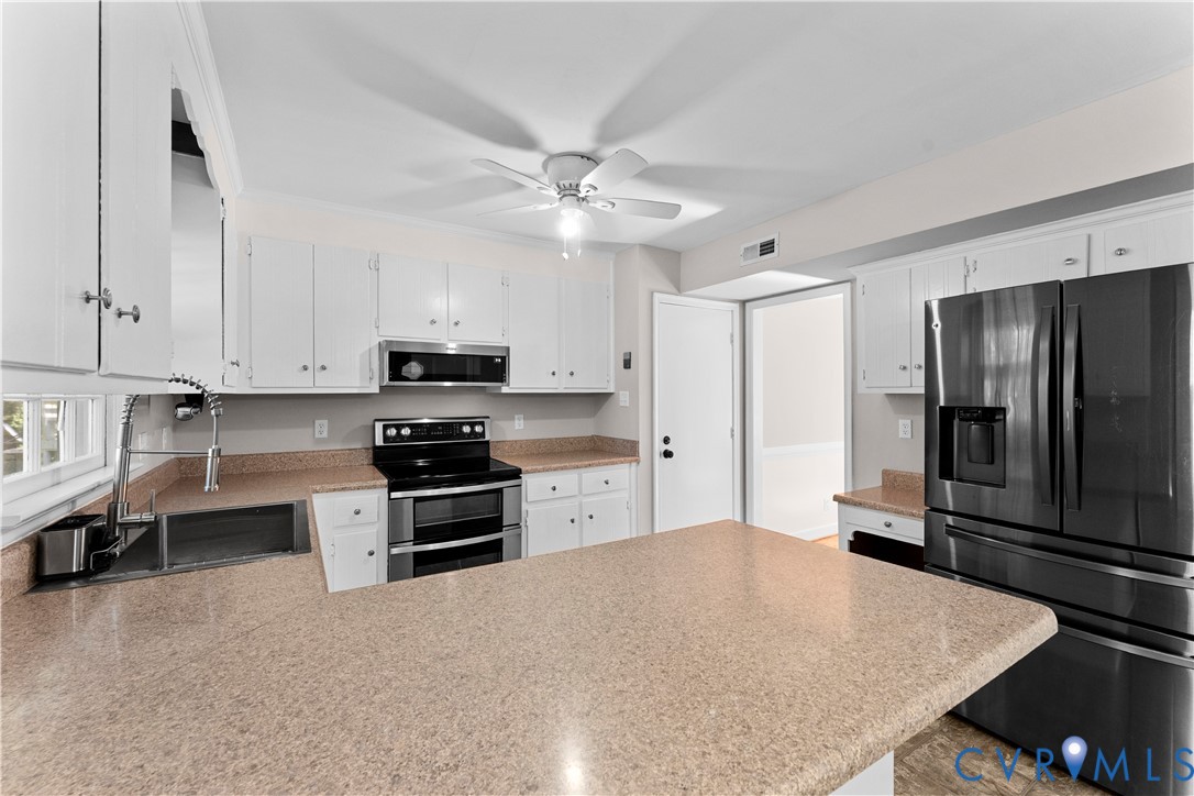 Kitchen featuring white cabinetry, solid-surface countertops, black-finish appliances, an undermount stainless steel sink with a high-arch pull-down faucet, and a ceiling-mounted fan
