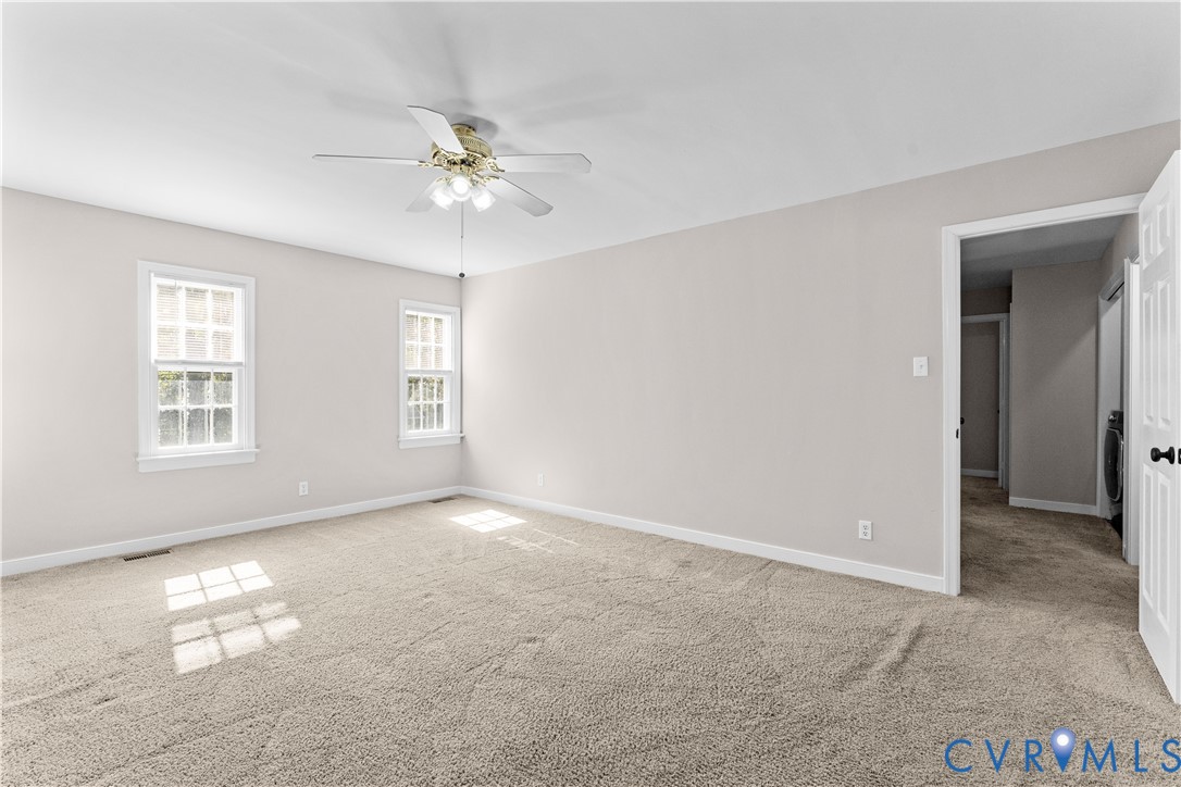 Neutral-toned wall finish, wall-to-wall carpeting, multi-pane windows, and a central ceiling fan with integrated lighting