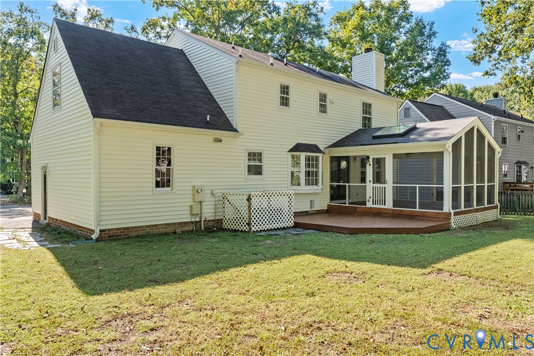 Exterior featuring light-colored horizontal siding, a screened-in porch with a skylight, an attached wooden deck, a bay window, and a chimney