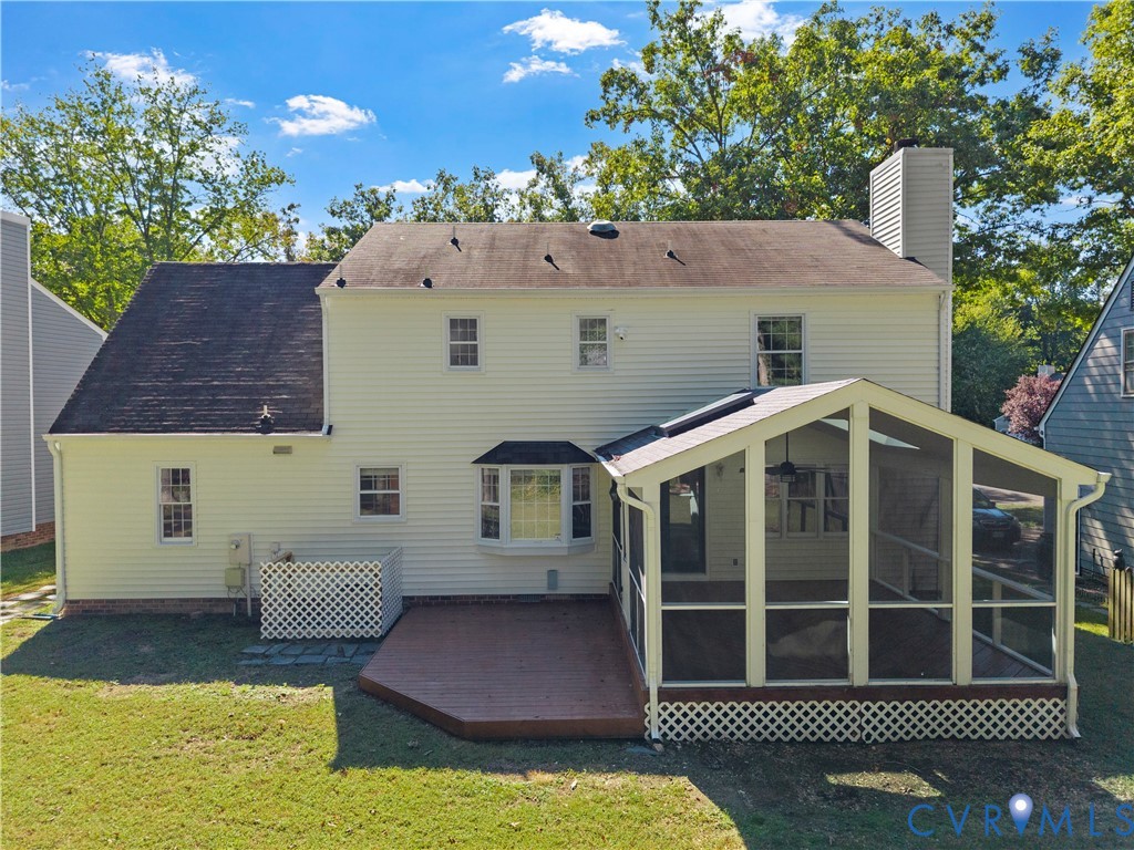 Rear exterior featuring a multi-paneled screened-in porch, wood-tone deck, bay window, and exterior chimney